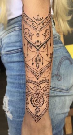 a woman's arm with tattoos on it and an intricate design in the middle