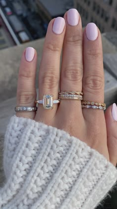 a woman's hand with three different rings on her fingers and one is wearing a white sweater