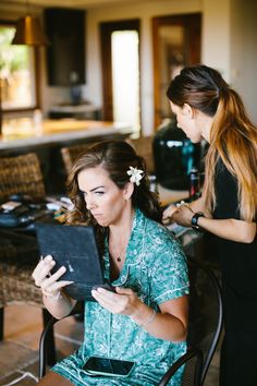 two women sitting in chairs looking at an electronic device