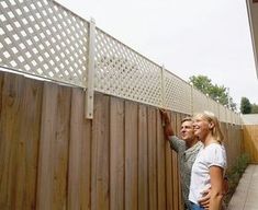 a man and woman leaning against a wooden fence