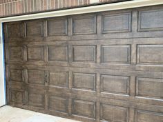 a brown garage door in front of a brick wall