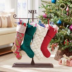 christmas stockings hanging on a clothes rack in front of a decorated christmas tree with presents