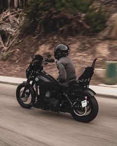 a man riding a motorcycle down the road in front of another person wearing a helmet