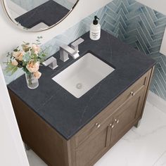 a bathroom sink with a mirror above it and flowers in a vase on the counter