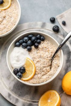 two bowls of oatmeal with blueberries and lemons on the side