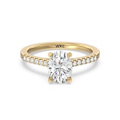 a yellow gold engagement ring with a cushion cut diamond and pave set diamonds around the band