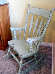 a white rocking chair sitting on top of a carpeted floor next to a dresser