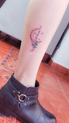 a woman's leg with a tattoo on it and a flower in the shape of a moon