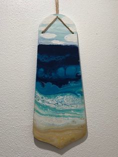 a wooden plaque hanging on a wall with blue and yellow paint in the ocean waves