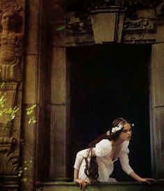 a woman sitting on the ledge of an old building