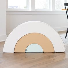 a child's play room with an arch shaped like a rainbow and chairs in the background