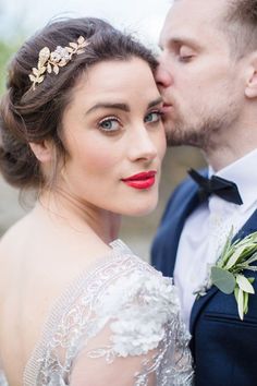 a man and woman kissing each other while wearing wedding hair pieces on their head,