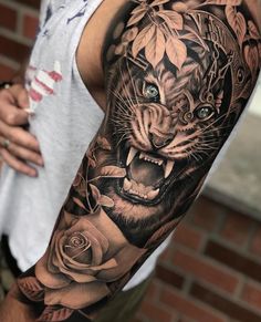 a man's arm with a tiger and roses tattoo on the left side of his arm