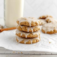 iced cookies stacked on top of each other next to a glass of milk