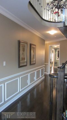 a staircase in an empty house with pictures on the wall and railings to the second floor