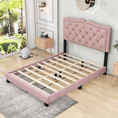 a pink bed frame sitting on top of a hard wood floor next to a window