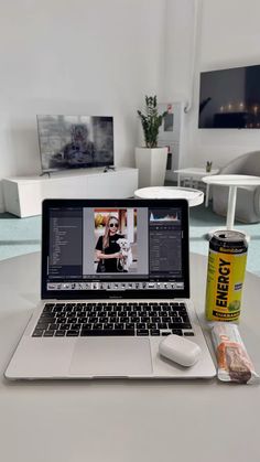 an open laptop computer sitting on top of a table next to a can of energy drink