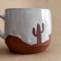 a white and brown coffee cup with a cactus design on the inside, sitting on a table