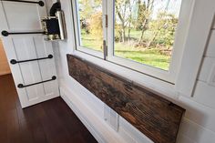 the inside of a tiny house with wood flooring and windows on each side of the door