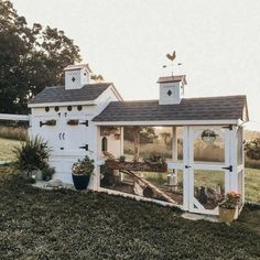 a small white house sitting on top of a lush green field