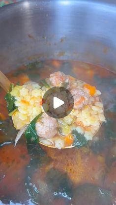 a ladle full of soup being stirred by a wooden spoon in a large pot