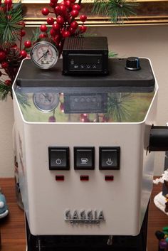 an old fashioned coffee machine sitting on top of a table next to a christmas tree