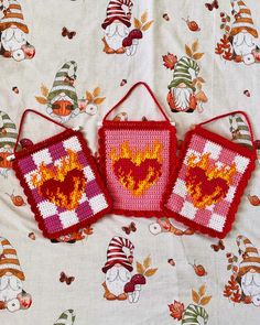 three cross stitch purses sitting on top of a bed