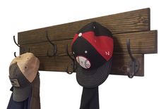 two hats are hanging on a wooden coat rack with hooks and hat clips attached to it