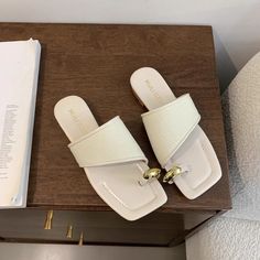 a pair of white slippers sitting on top of a wooden table next to a book