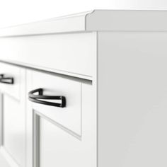 a white cabinet with two black handles and some drawers on it's side wall