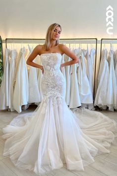 a woman standing in front of a rack of wedding dresses