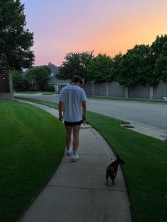 a woman walking her dog down the sidewalk