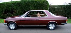 a woman sitting in the driver's seat of a maroon car