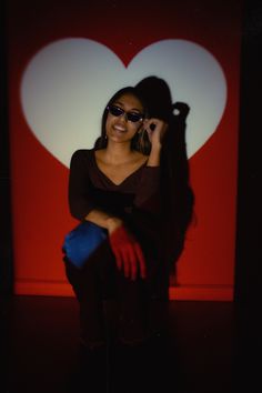 a woman sitting in front of a red heart