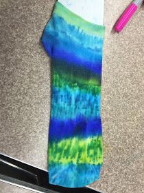 a tie - dyed shirt is laying on the floor next to a pair of scissors