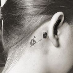 a woman's behind the ear tattoo with an image of a man and dog on it