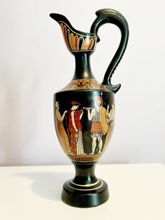 an antique vase with people painted on the front and sides, sitting on a white surface