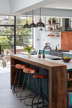 a kitchen island with three stools next to it and an oven in the background