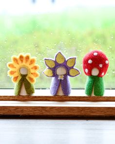 three small stuffed mushrooms sitting on top of a window sill next to a flower