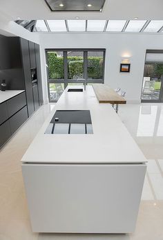 an empty kitchen with white counter tops and black cabinets on the walls, along with large windows