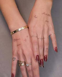 two women's hands with tattoos and rings on their fingers, both holding each other