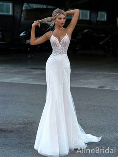 a woman in a white wedding dress posing for the camera with her arms behind her head