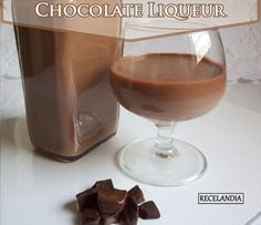 a glass of chocolate next to a bottle of liquid