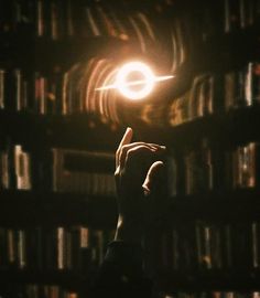 a person holding their hand up in front of a bookshelf