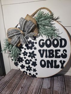 a wooden sign that says good vibes only with pine branches and bows on it