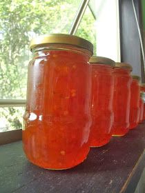 four jars filled with liquid sitting on top of a wooden table next to a window