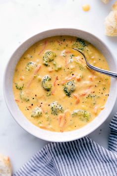 a white bowl filled with broccoli and cheese soup on top of a blue towel