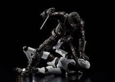 the action figure is posed in black and white with his hands on his knees, holding a knife