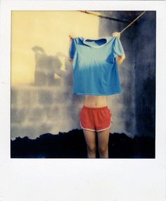 a woman in red shorts and a blue shirt hanging on a clothes line with her hands behind her head