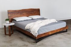 a bed sitting in a bedroom next to a table with a potted plant on it